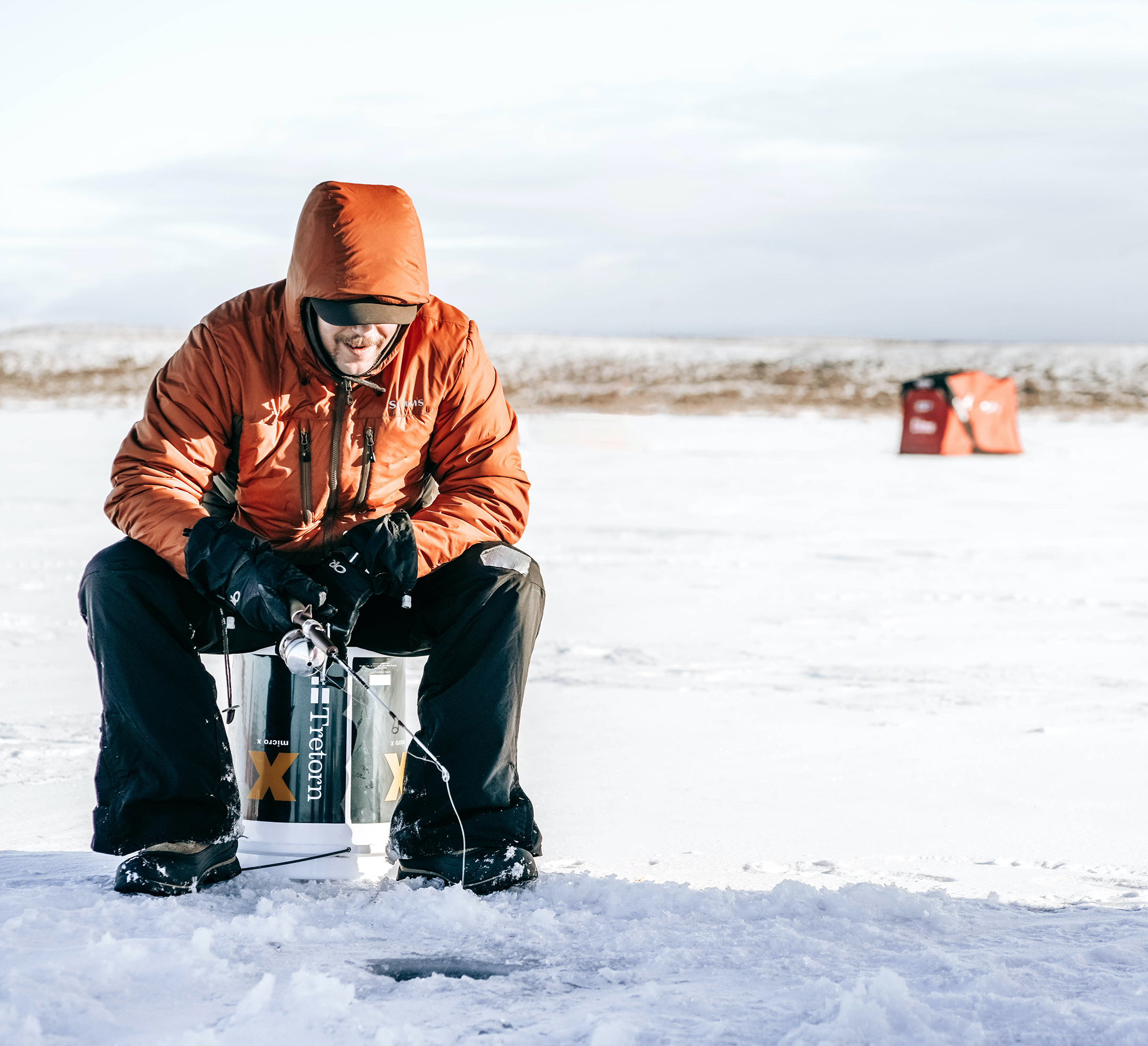 A man ice fishing outside in the winter