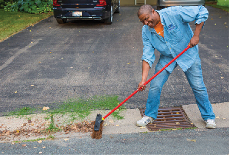 A man clears lawn clippings away from storm drain